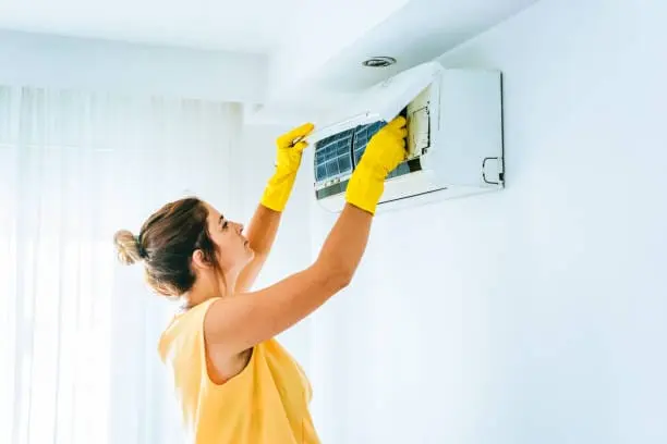 Chica limpiando filtro de aire acondicionado
